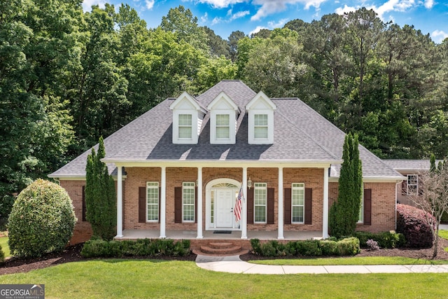 cape cod house featuring a front yard and covered porch