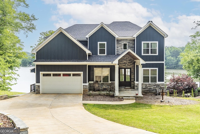 craftsman inspired home featuring a garage, a front lawn, a porch, and a water view