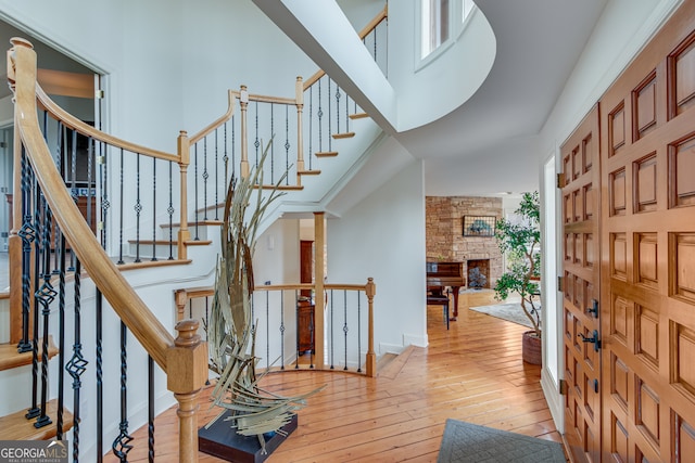 foyer entrance with a towering ceiling and light wood-type flooring