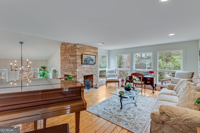 living room featuring a stone fireplace, a wealth of natural light, and light hardwood / wood-style floors