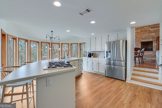 kitchen featuring stainless steel appliances, a center island, white cabinets, and decorative light fixtures