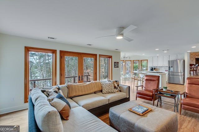 living room with french doors, ceiling fan, and light wood-type flooring