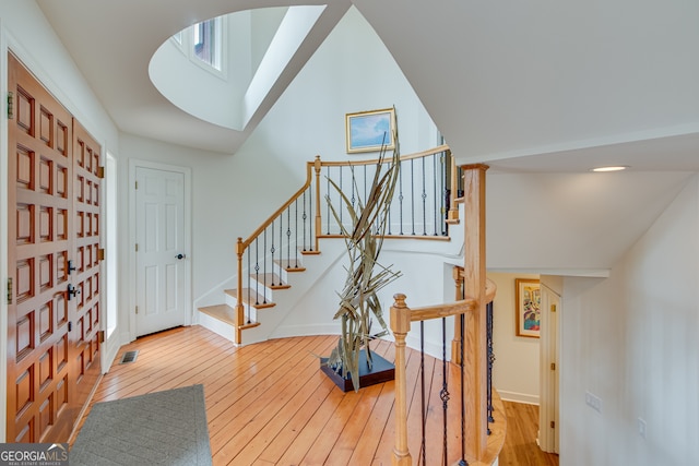 staircase featuring hardwood / wood-style flooring and high vaulted ceiling