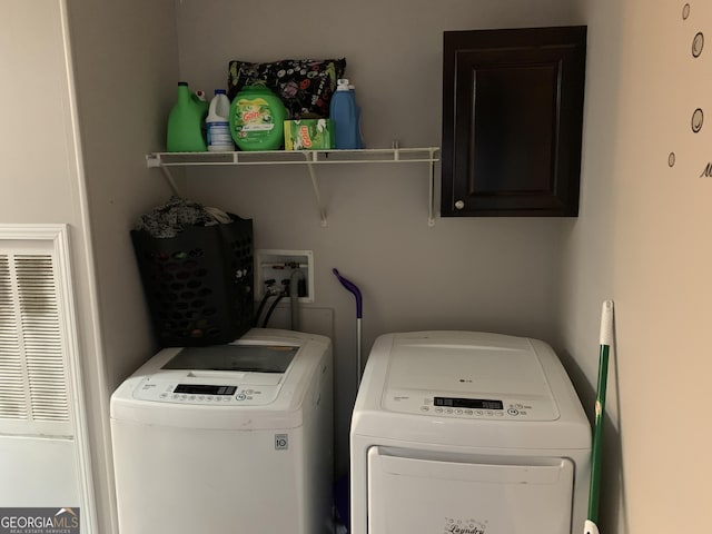 clothes washing area with a heating unit, cabinet space, and washing machine and clothes dryer