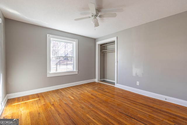 unfurnished bedroom with hardwood / wood-style flooring, a textured ceiling, a closet, and ceiling fan