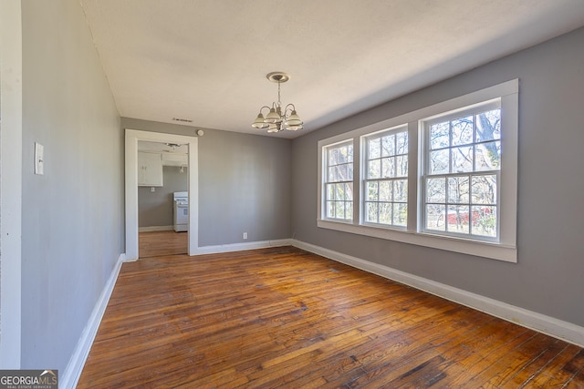 unfurnished dining area with a notable chandelier and dark wood-type flooring