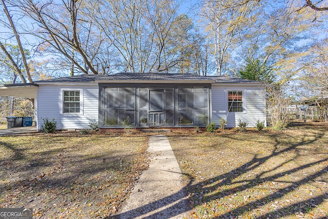 view of front facade featuring a carport, a front lawn, and a sunroom