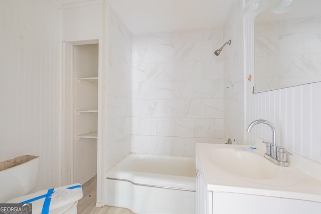 full bathroom with hardwood / wood-style flooring, tiled shower / bath, vanity, and toilet