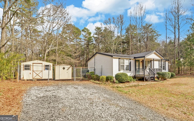 view of front facade featuring fence, a shed, a porch, a front yard, and an outdoor structure