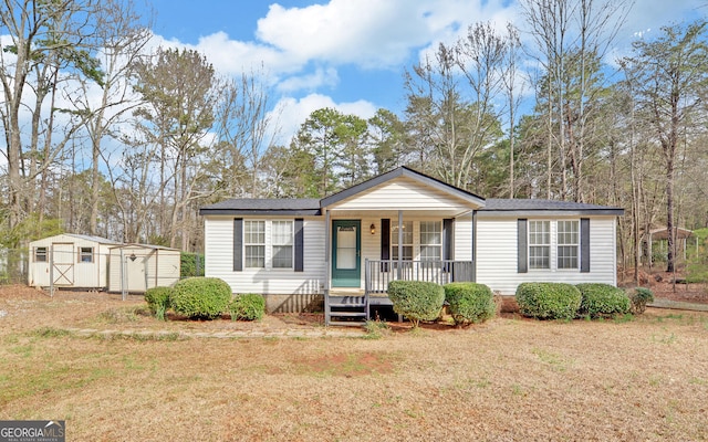 view of front of property featuring a porch, a storage unit, an outbuilding, and a front lawn