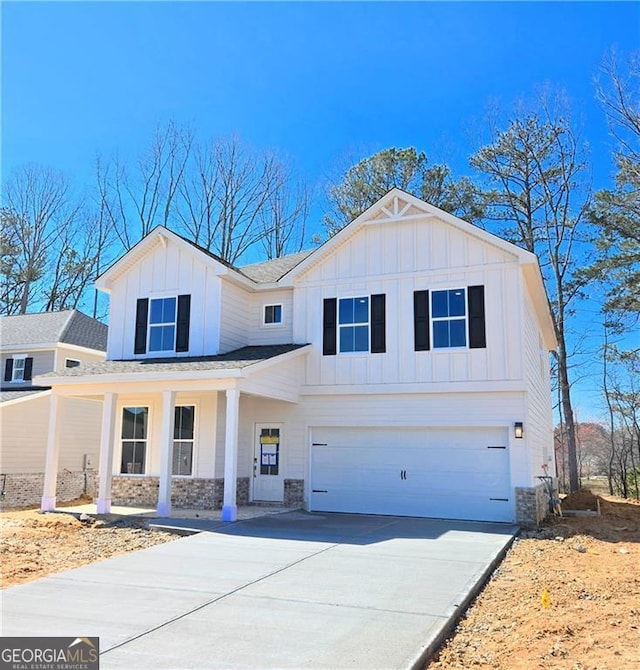 modern farmhouse style home with a garage, stone siding, board and batten siding, and concrete driveway