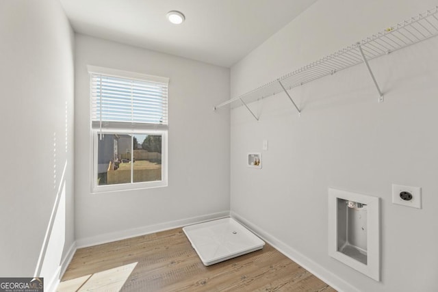 clothes washing area with laundry area, baseboards, hookup for a washing machine, hookup for an electric dryer, and light wood-style floors