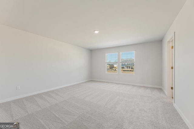 spare room with light carpet and baseboards