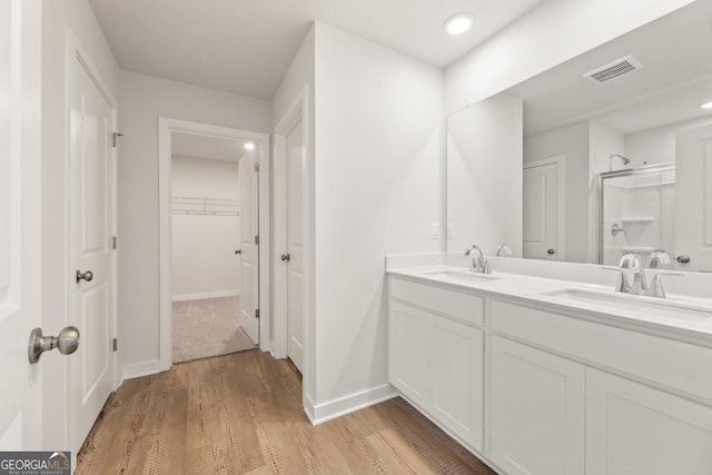 bathroom with visible vents, a sink, a shower stall, and a spacious closet