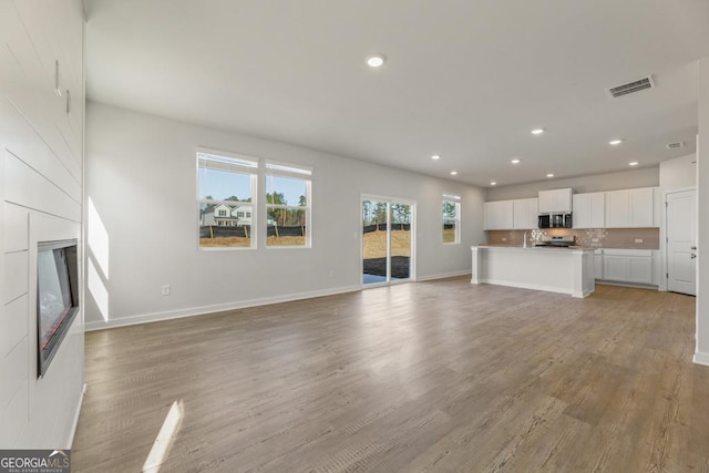 unfurnished living room featuring light wood-style flooring, recessed lighting, a fireplace, visible vents, and baseboards