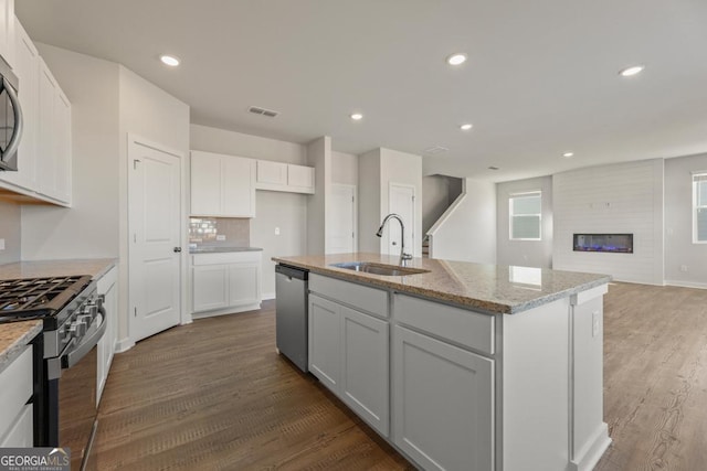 kitchen featuring recessed lighting, stainless steel appliances, wood finished floors, a sink, and white cabinets