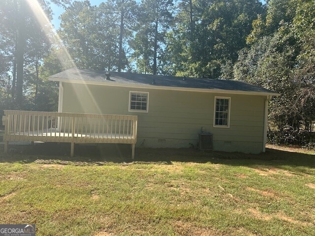 view of side of home featuring a wooden deck, a yard, and central AC