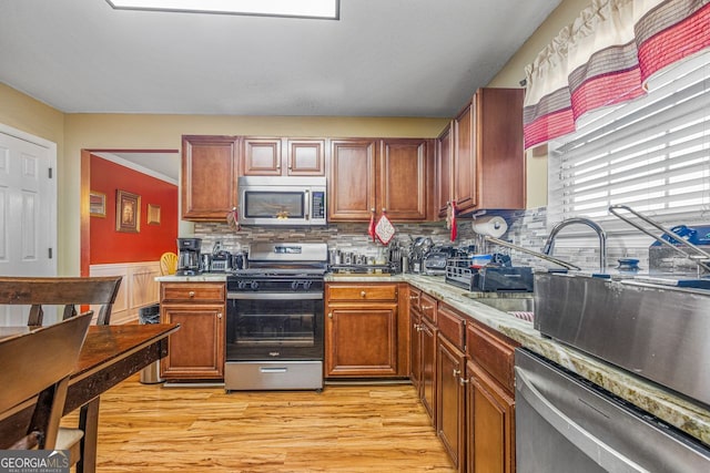 kitchen featuring appliances with stainless steel finishes, light hardwood / wood-style floors, and decorative backsplash