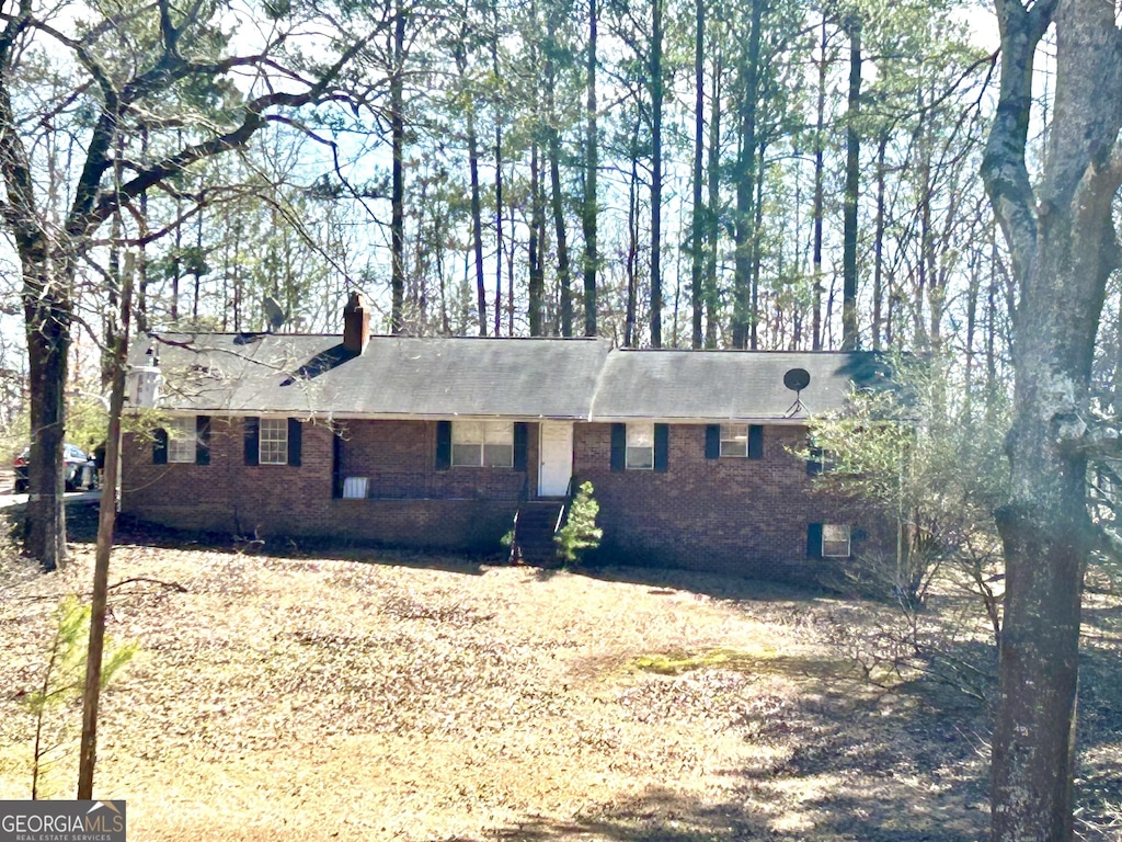 ranch-style home featuring brick siding and a chimney