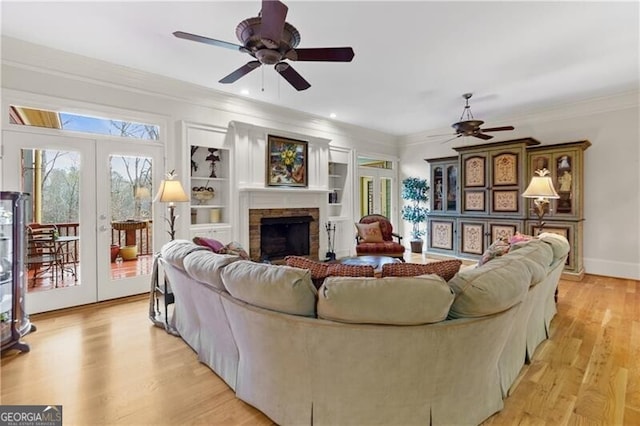 living room featuring ornamental molding, a ceiling fan, french doors, and a fireplace