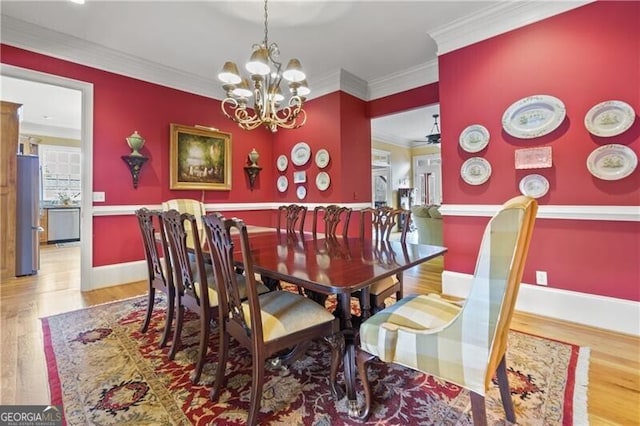 dining room with baseboards, wood finished floors, a notable chandelier, and crown molding