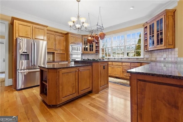 kitchen with light wood finished floors, an inviting chandelier, open shelves, brown cabinetry, and appliances with stainless steel finishes