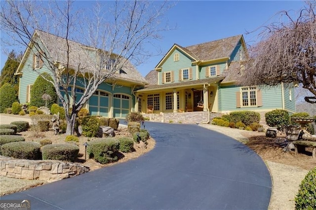 traditional-style home featuring a porch, a garage, and aphalt driveway