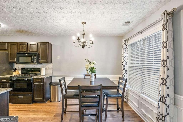 dining room with a textured ceiling, light hardwood / wood-style flooring, and a chandelier