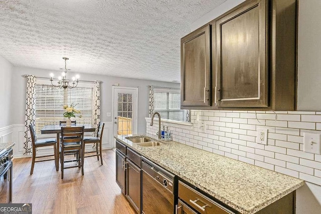 kitchen featuring light stone countertops, dark brown cabinets, sink, and dishwashing machine