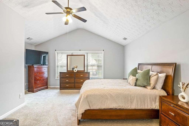 bedroom with ceiling fan, vaulted ceiling, light carpet, and a textured ceiling