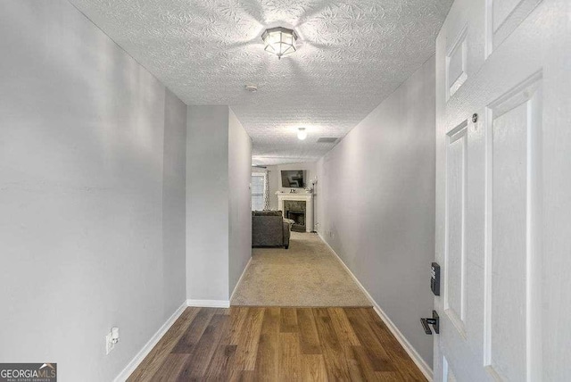 hallway with hardwood / wood-style floors and a textured ceiling