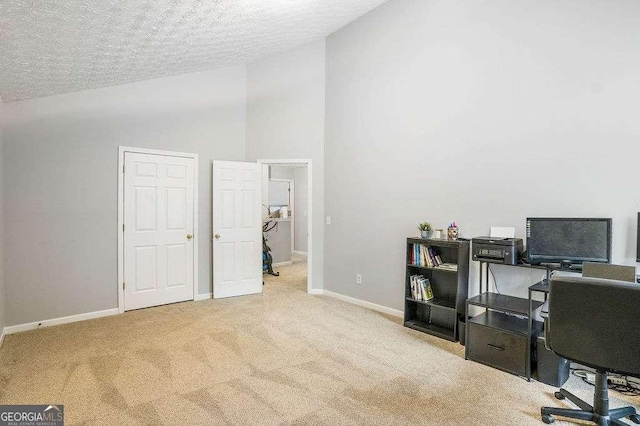 office area featuring high vaulted ceiling, light carpet, and a textured ceiling