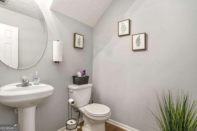 bathroom featuring vaulted ceiling, hardwood / wood-style floors, a textured ceiling, and toilet