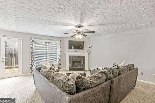 carpeted living room with ceiling fan, a premium fireplace, and a textured ceiling