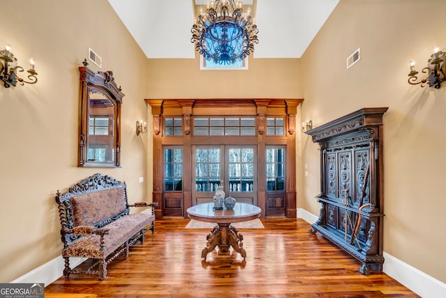 entryway featuring hardwood / wood-style floors, high vaulted ceiling, and a chandelier