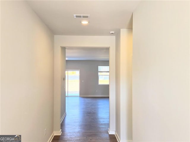 hallway featuring dark wood-style flooring, visible vents, and baseboards