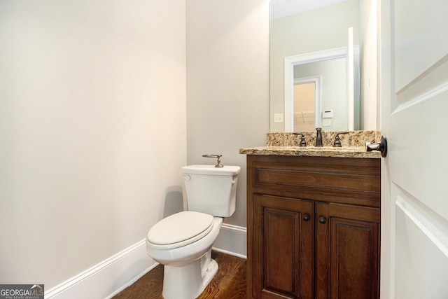bathroom with wood finished floors, vanity, toilet, and baseboards