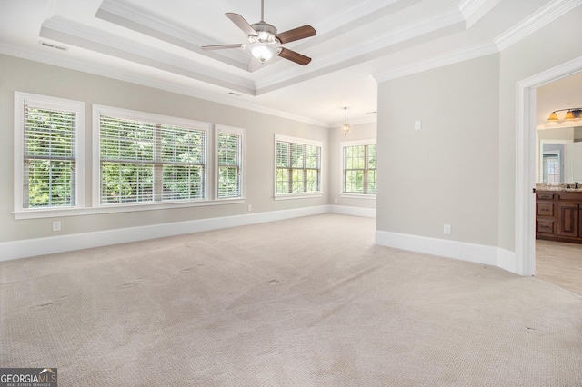 spare room with a tray ceiling, ornamental molding, light colored carpet, ceiling fan, and baseboards