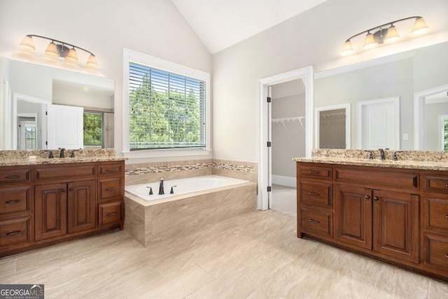 bathroom featuring vaulted ceiling, a garden tub, and two vanities