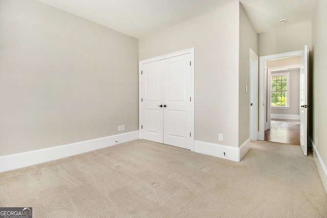 unfurnished bedroom featuring light carpet, baseboards, and a closet