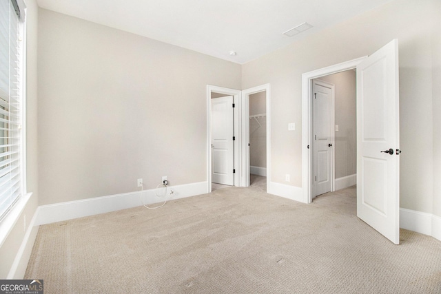 unfurnished bedroom featuring carpet floors, a spacious closet, baseboards, and a closet