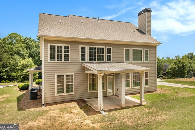 back of property with a patio, cooling unit, a chimney, and a yard