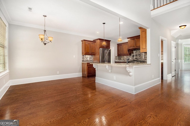 kitchen featuring high end fridge, dark wood-style flooring, a kitchen breakfast bar, brown cabinets, and a chandelier