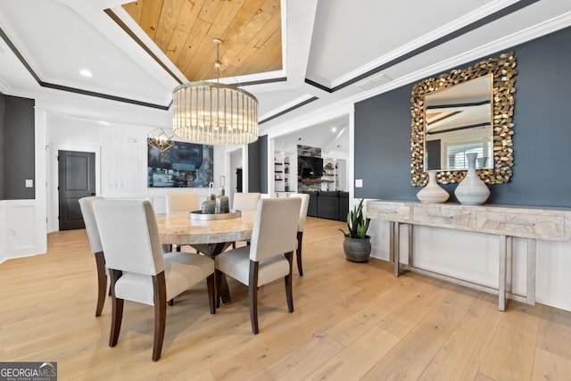 dining room featuring crown molding, light wood-type flooring, an inviting chandelier, and a tray ceiling