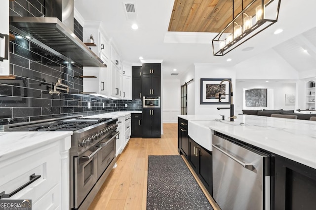 kitchen with stainless steel appliances, light stone counters, white cabinets, decorative light fixtures, and light wood-type flooring