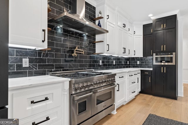 kitchen featuring white cabinetry, stainless steel appliances, and wall chimney range hood