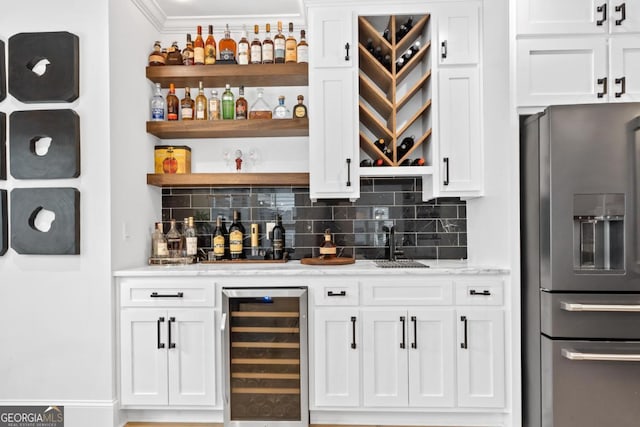 bar featuring wine cooler, white cabinetry, stainless steel fridge, and tasteful backsplash