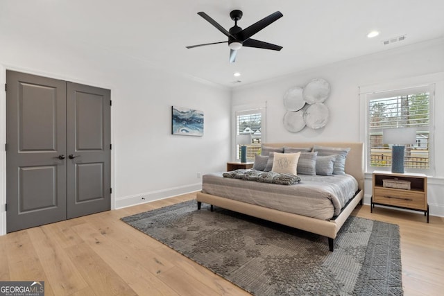 bedroom featuring hardwood / wood-style flooring, ornamental molding, and multiple windows