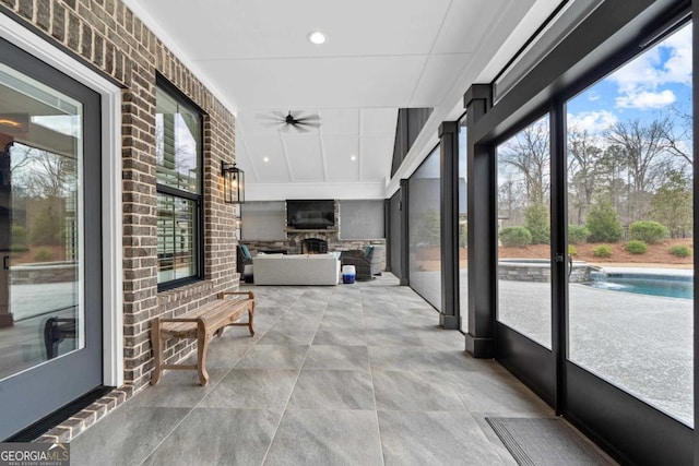 sunroom / solarium with a fireplace and ceiling fan