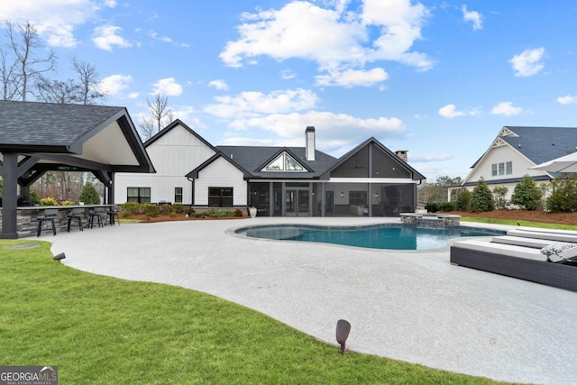 view of pool with an outdoor bar, a yard, a patio area, a sunroom, and an in ground hot tub